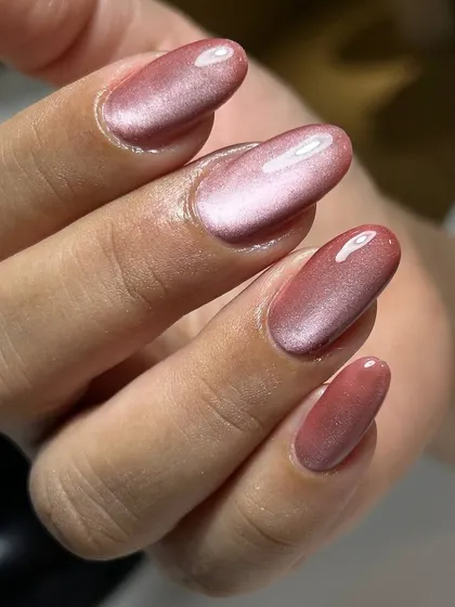 A beautiful rose-gold cat-eye manicure on oval-shaped nails. The warm, shimmery tones are both elegant and on-trend.