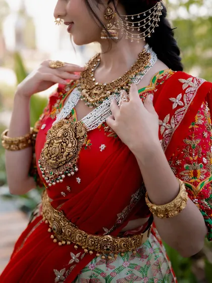 A detailed shot of the bride's stunning temple jewellery. The focus on the intricate design of the necklace and belt highlights the craftsmanship and cultural richness of her attire.