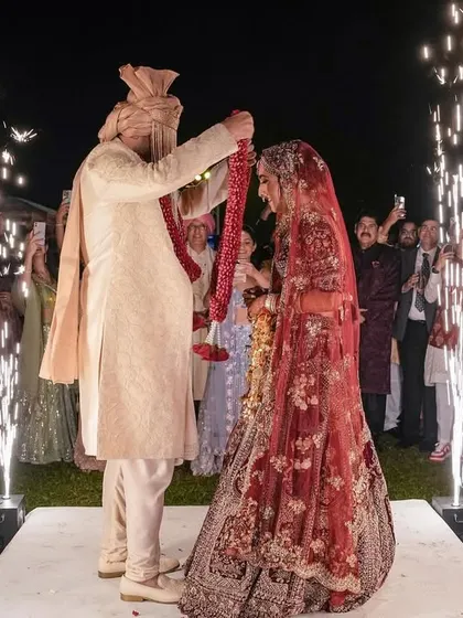 The moment of exchange. The groom places the garland on his bride, surrounded by sparkling cold pyros, marking their union.