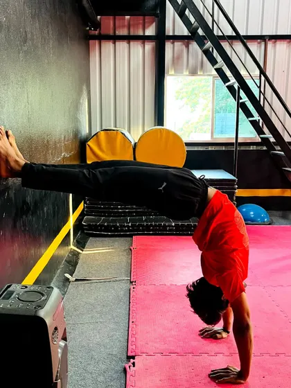 A wall-assisted handstand push-up or hold is an advanced conditioning exercise that builds incredible upper body strength.