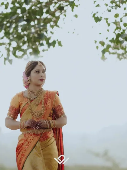 A wide shot of a bride in a beautiful saree against a misty, natural landscape, creating a sense of grandeur and romance.