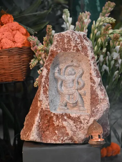 A rock carving of a deity, displayed amidst flowers as part of our Makar Sankranti collection. These pieces, created by talented artisans, celebrate our cultural heritage and the beauty of natural materials.