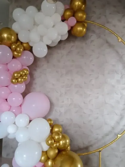 A closer look at the elegant pink, white, and gold balloon ring. The combination of different balloon sizes and chrome accents gives it a professional and luxurious feel.
