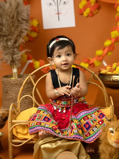 Holding a tiny bow and arrow, this little girl is ready for Dussehra. These themed props add a playful and meaningful element to the photos.