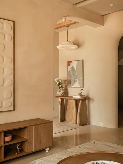 The entryway sets the home's philosophical tone with a sculptural wood console. Its organic form, paired with abstract art and a pleated pendant light, makes every arrival feel grounding and uplifting.