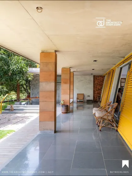 The expansive verandah at "Aamra" provides a sheltered connection between different parts of the house. The polished Kota stone flooring reflects the natural light, enhancing the sense of space and openness.