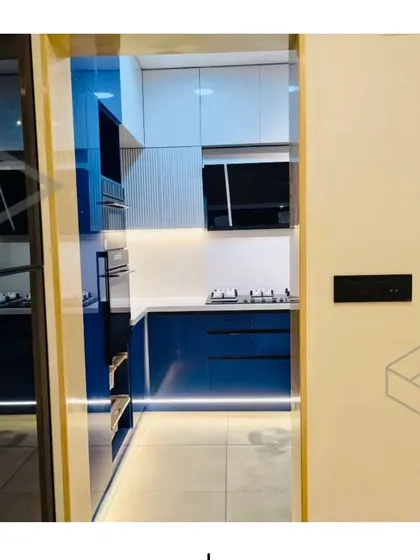 These images provide multiple angles of the stunning blue and white modular kitchen, showing details like the built-in oven tower, the fluted cabinet finish, and the overall clean and spacious layout.