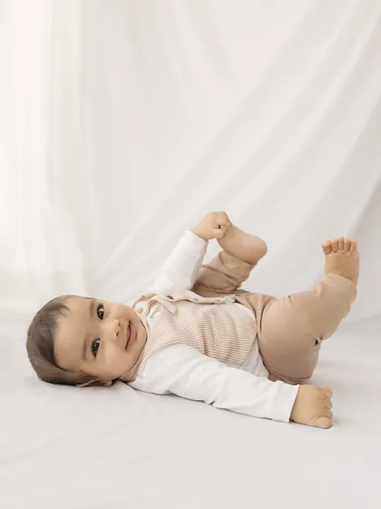 A simple and sweet portrait. This six-month-old, lying on a clean white backdrop, shows off his happy and relaxed personality.