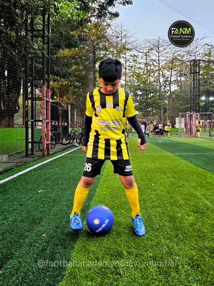 Focused and ready, a young player stands with the ball at his feet. This pose shows the confidence and readiness I instill in my athletes.