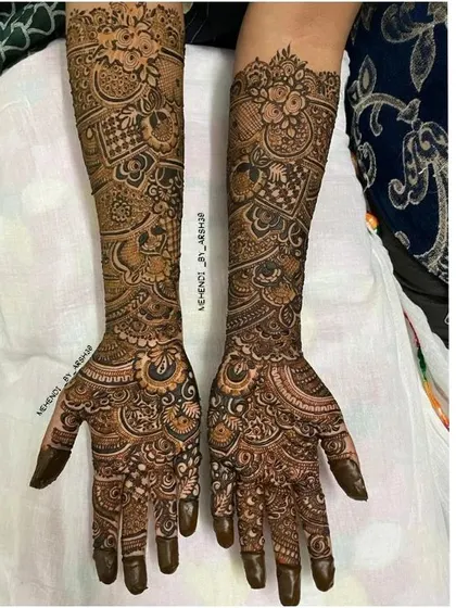 The beauty of a fresh henna application. This design features dense patterns on the palm and a beautiful cuff design on the wrist, combining different artistic elements.