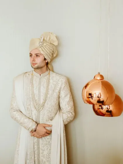 A handsome portrait of the groom in his elegant sherwani and safa, captured in a moment of quiet reflection.