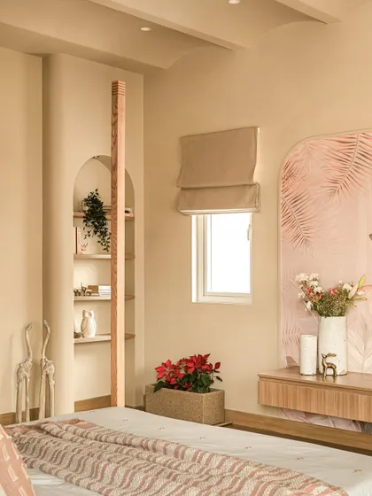 A strategically placed display corner next to a window, featuring an arched alcove and integrated bookshelf. The coral-toned wallpaper and handpicked ceramics create a dialogue between craft and architecture.