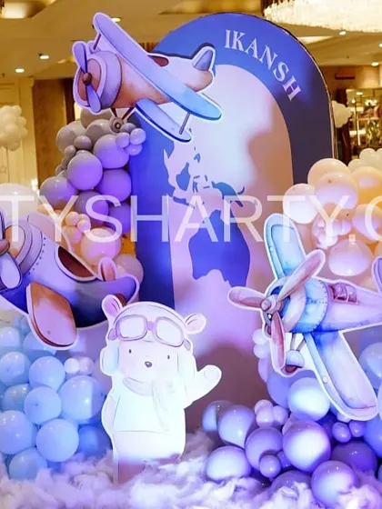 A creative combination of a travel and teddy bear theme, featuring a large prop with airplanes flying around a globe with a cute aviator bear.