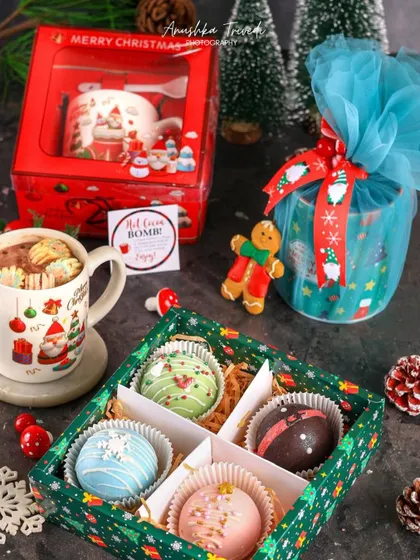 A complete hot cocoa bomb gift set, showing the product both in its packaging and ready to be enjoyed in a mug.