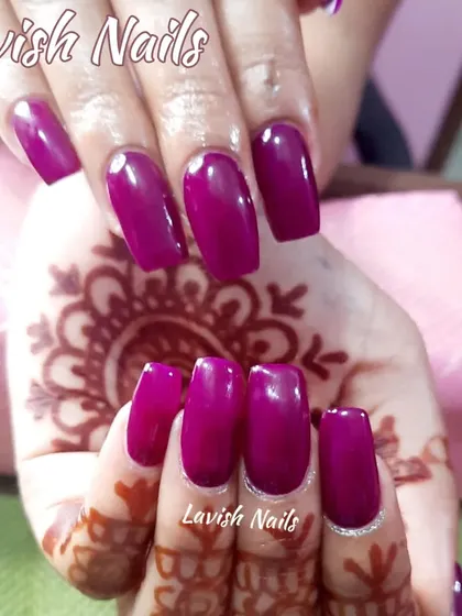 Bold, glossy magenta nails in a square shape provide a stunning pop of color that enhances the beauty of traditional mehendi patterns.