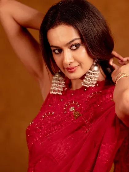 A close-up on the intricate details of the red outfit and the beautiful silver earrings. The pose is soft and elegant.