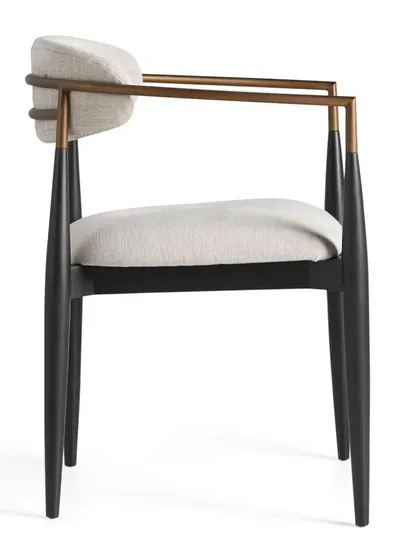 A side profile of the Jagger armchair, highlighting the contrast between the dark mahogany frame, the warm metal, and the light upholstery.