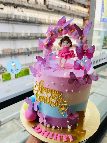 A beautiful ballerina and butterfly cake for a first birthday. This striped pastel cake is adorned with a dancing ballerina topper under an arch of butterflies.