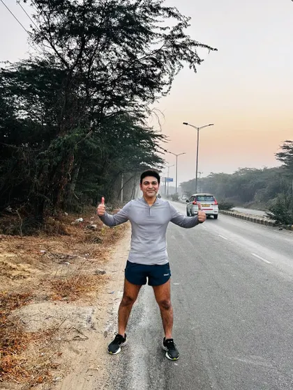 A lone runner from our tribe, thumbs up, enjoying the solitude of the open road. We train you to be strong both with the group and on your own.