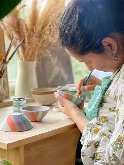 A student paints delicate, colorful stripes on a set of bowls, a highlight from a week of easing back into the studio rhythm.
