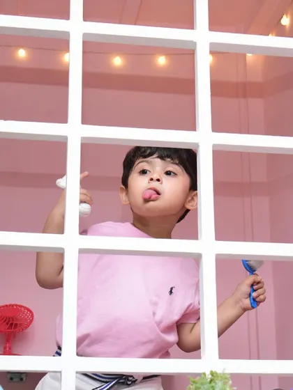A playful boy peeks through the window of the playhouse, showing off his silly side.