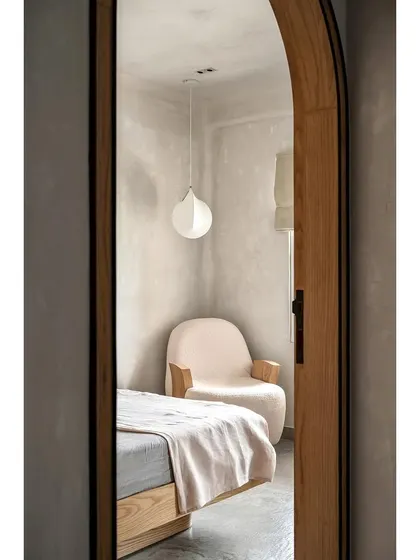 A view through the arched doorway into the 'Unmei' bedroom, highlighting the cozy reading nook. The custom lounge chair and soft lighting create an inviting corner to relax and unwind.