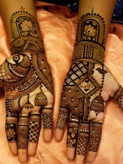 This design combines several auspicious elements for Karwachauth, including jhumka motifs, swastikas for good fortune, and a space to write a name. The intricate check patterns and floral work make it a traditional yet personalized choice.
