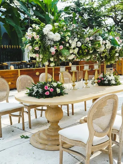 An elegant dining table setup for a wedding reception. The tall floral centerpieces and classic wooden chairs create a timeless and sophisticated look.
