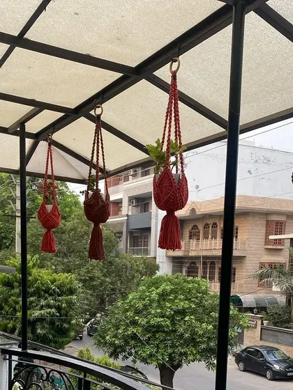 A customer photo showing my red hanging planters on their balcony. They add such a vibrant pop of color.