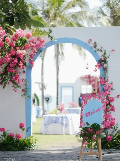 A picturesque Mehendi setup on the lawns of a Thailand resort, with a floral-draped archway overlooking the sea.
