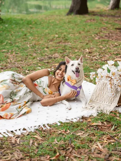 A happy dog mom with her white Indie dog during an outdoor Mother's Day session.