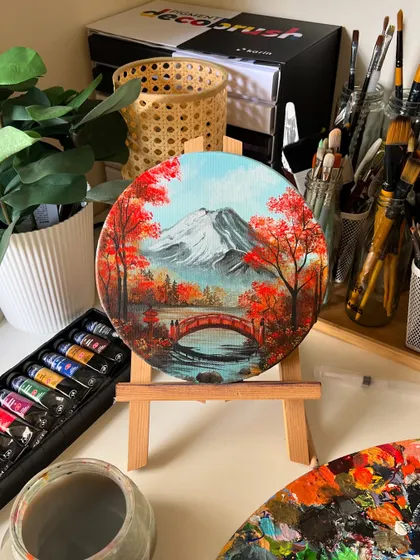 The finished round canvas painting of Mt. Fuji, displayed on a mini easel in my studio. The colors are so vibrant and warm.