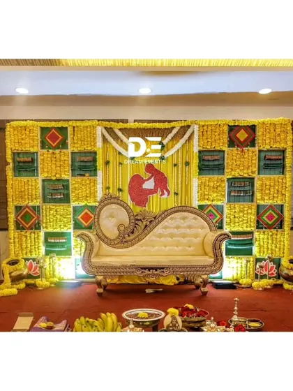 A traditional baby shower backdrop made with a checkered pattern of marigolds and banana leaves. The mother and child motif adds a sweet, personal touch to the decor.