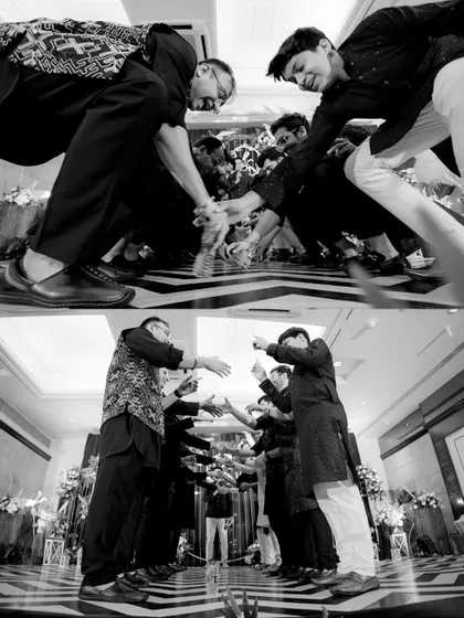 A creative, low-angle black and white shot of the groomsmen performing a dance routine at the Sangeet.