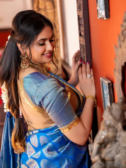 A candid moment from the shoot, showing the beautiful texture of the saree and the intricate coin detailing on the blouse sleeve.