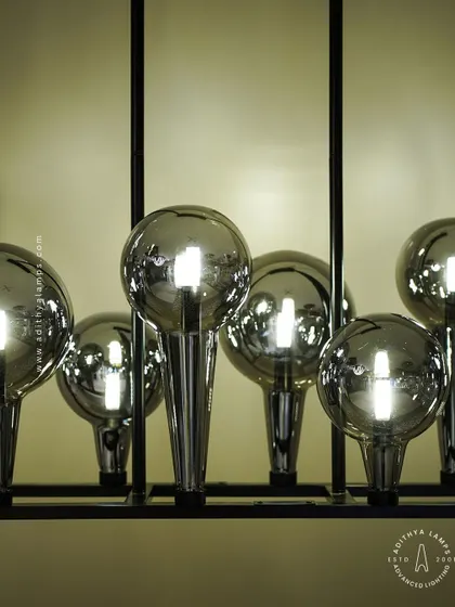 A playful yet chic linear chandelier featuring a series of chrome-finished glass bubbles. The highly reflective surface and modern design make it a striking addition to a kitchen island or a contemporary dining space.