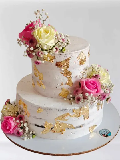 A rustic semi-naked cake decorated with fresh flowers and gold leaf. This style is very popular for weddings and anniversaries due to its natural and effortless beauty.