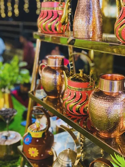 A collection of ornate, hand-painted and copper tea kettles on display.