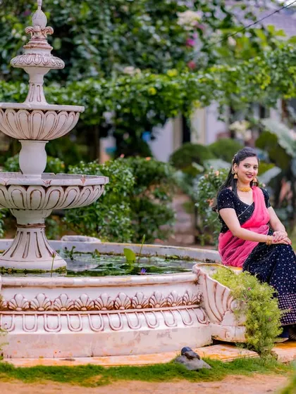 An elegant portrait by a classic white fountain. The couple's stylish outfits and the beautiful garden setting create a very sophisticated pre-wedding photo.