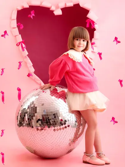 A sweet and simple pose from our Valentine's mini-session. The girl's gentle expression and the playful pink setup make for a lovely and timeless photo.