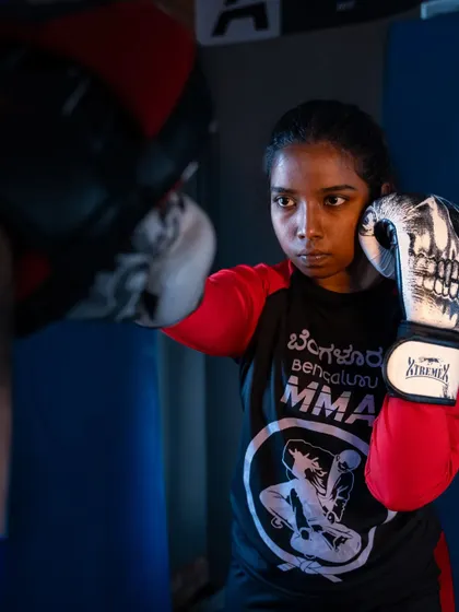 Focus and determination. A student practices her striking on the pads, wearing our Bengaluru MMA shirt with pride. This is where you build power, precision, and the confidence that comes with knowing you can land a solid hit.