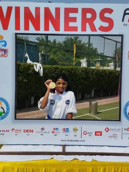 A gold medalist poses in the winner's frame, celebrating her victory.