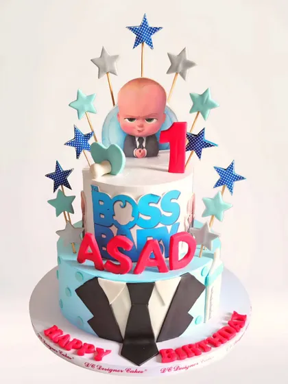 A two-tier Boss Baby cake for a first birthday. This fun whipped cream cake features the iconic suit and tie on the bottom tier and the Boss Baby himself on top, surrounded by stars.