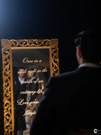 A beautifully crafted welcome mirror with an ornate gold frame, personalized with a quote about love. It serves as a heartfelt decor piece and a wonderful photo opportunity for the couple and guests.