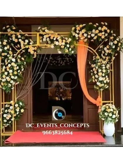 An elegant entrance decor setup for a home-based event. The golden frames adorned with white and peach florals create a sophisticated and welcoming doorway.