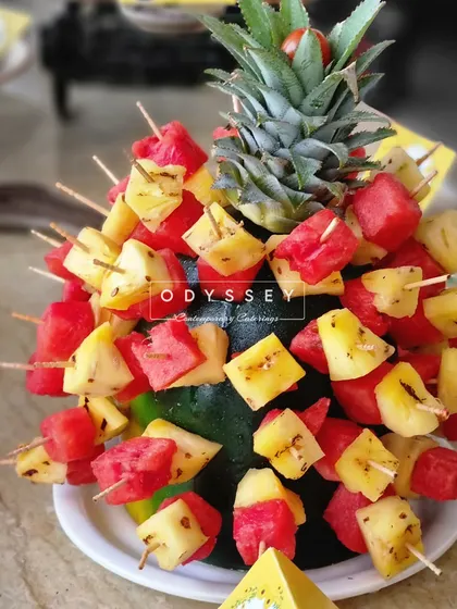A creative fruit display using a pineapple as the centerpiece for watermelon and pineapple skewers. This adds a tropical and festive touch to any buffet or grazing table.