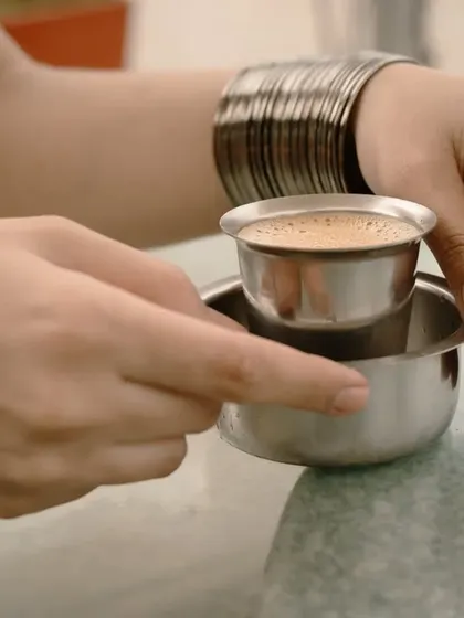 A shot focusing on the hands holding a traditional South Indian filter coffee. This style of photography tells a story and evokes a feeling of comfort and tradition.