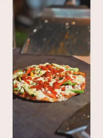 A freshly made Mexican Chipotle Pizza, ready to be sliced and served. The rustic presentation on a wooden board adds to its appeal.