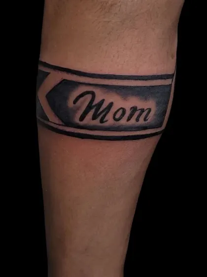 A "Mom" tattoo designed as part of a simple armband.
