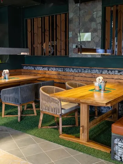 A detailed shot of the seating area at Social Offline, showing the mix of wood, stone, and greenery that defines its unique aesthetic.